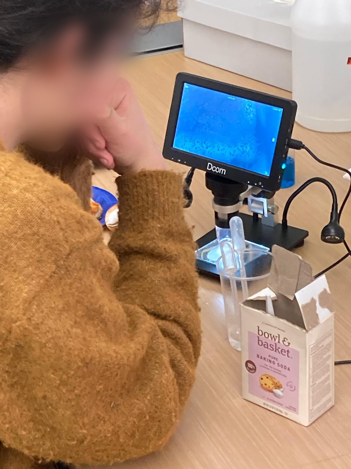 child looking at an electronic microscope with bacteria on its screen