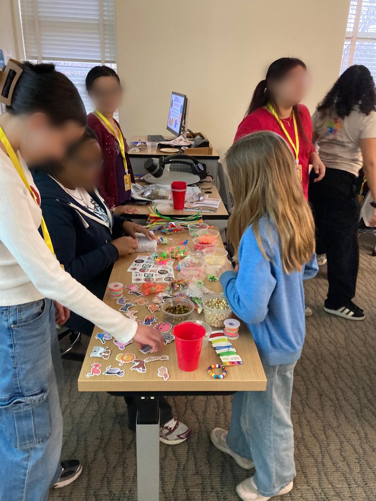 People around table making beaded charms